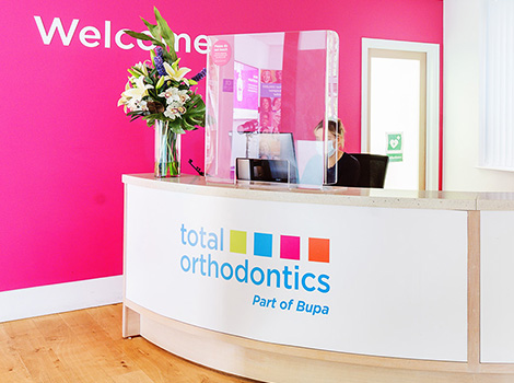 Reception desk with pink wall at Total Orthodontics Haywards Heath