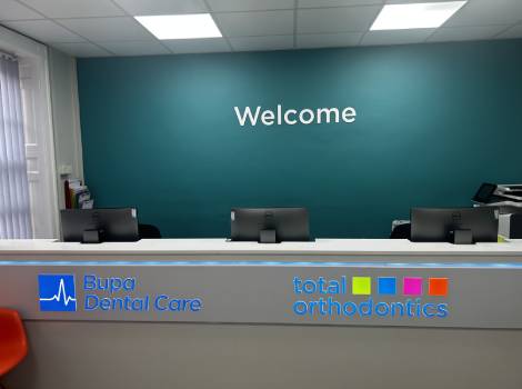 The reception desk of Total Orthodontics Kidderminster has teal wall behind it