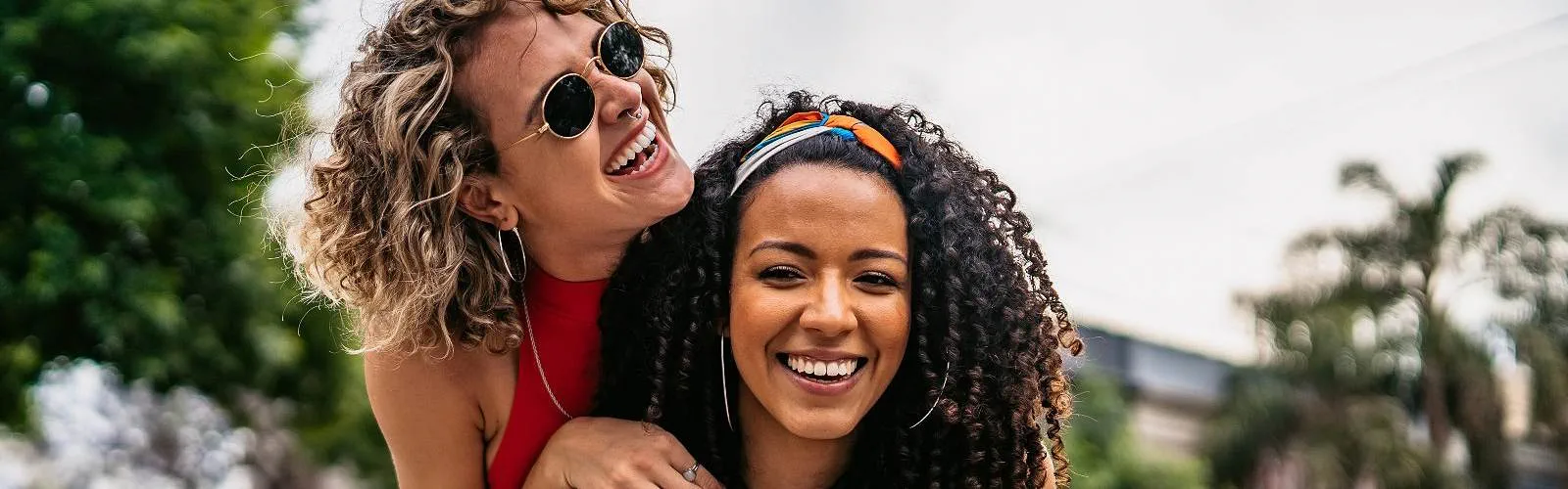 Two friends hugging each other smiling and laughing outside