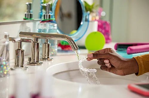 Person rinsing Invisalign aligners under bathroom tap