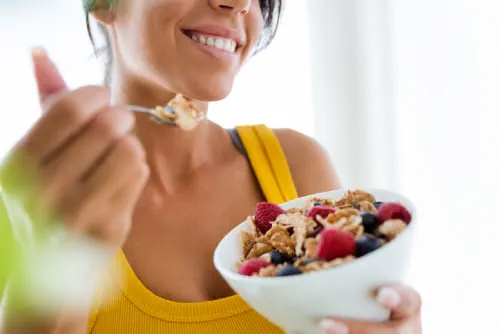  woman eating cereals and fruits at home