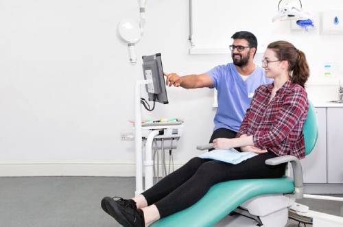A woman sits in the dentsit chair inside the practice, helping her become more familiar with the space and overcome her fear of the orthodontist