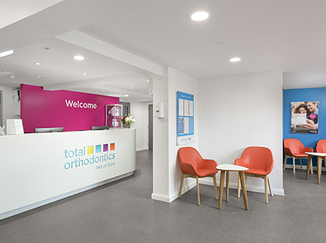 Reception area at Total Orthodontics Crawley with orange chairs for patient use