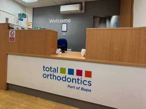 Reception desk at Total Orthodontics Stockport has a grey wall behind it