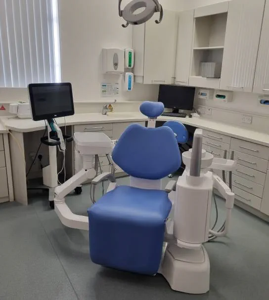 A clean and modern dental surgery at Total Orthodontics Tunbridge Wells with light from a window shining on to the dentist chair and equipment