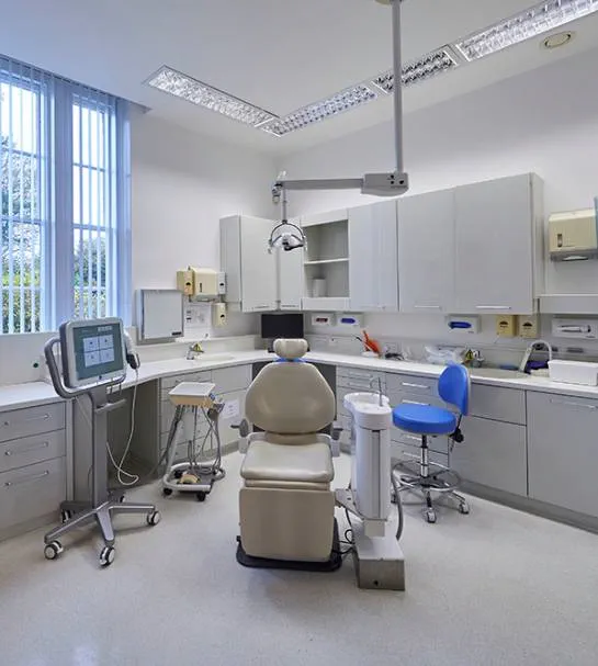 A clean and modern dental surgery at Total Orthodontics Tunbridge Wells with light from a window shining on to the dentist chair and equipment
