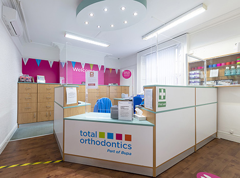 Total Orthodontics Warrington reception desk with colourful Total Orthodontics logo