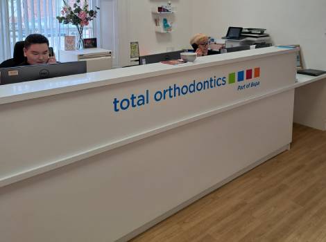 Total Orthodontics Warrington reception desk with colourful Total Orthodontics logo