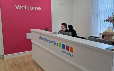 Total Orthodontics Warrington reception desk with colourful Total Orthodontics logo